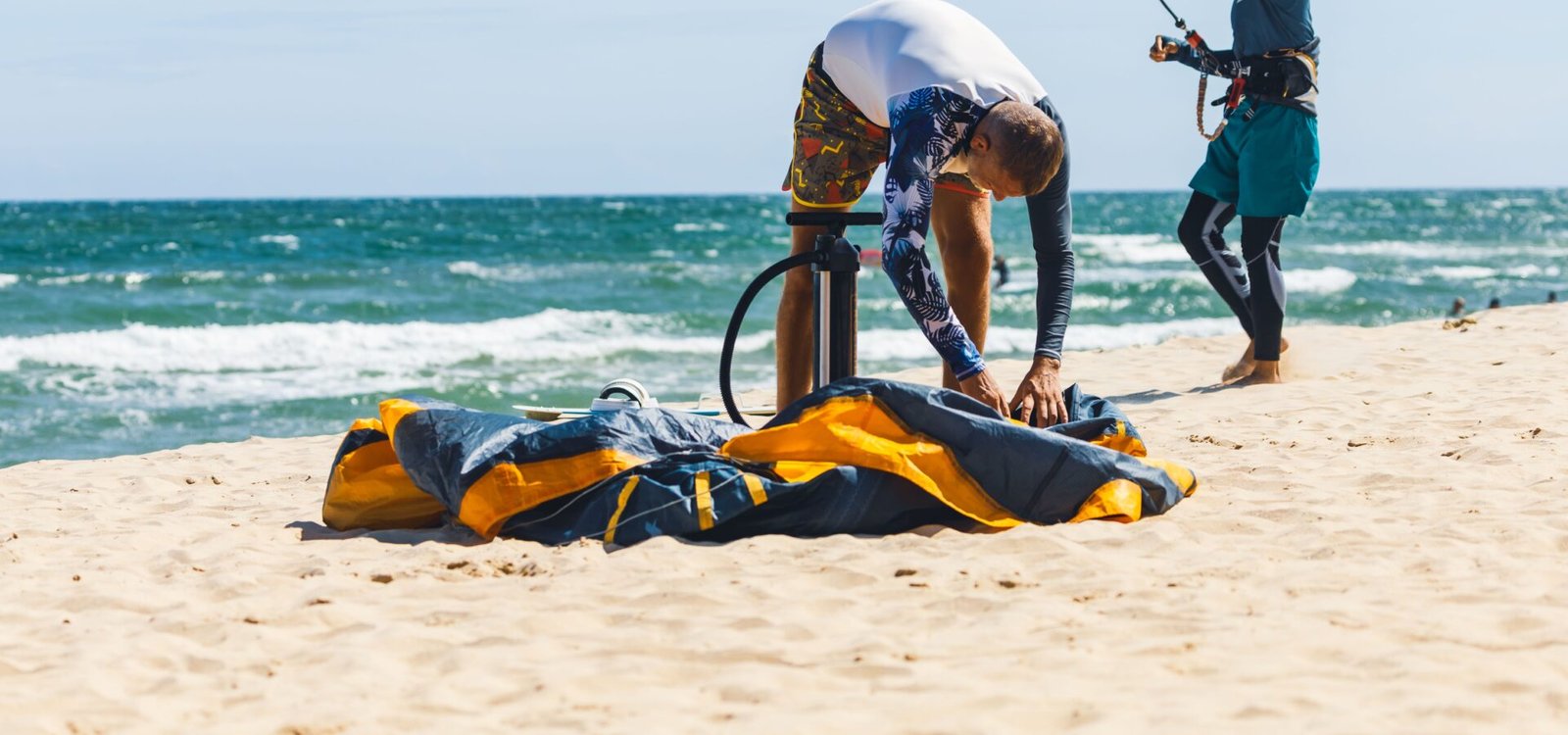 Un rider gonflant son aile de kitesurf sur la plage avant une session