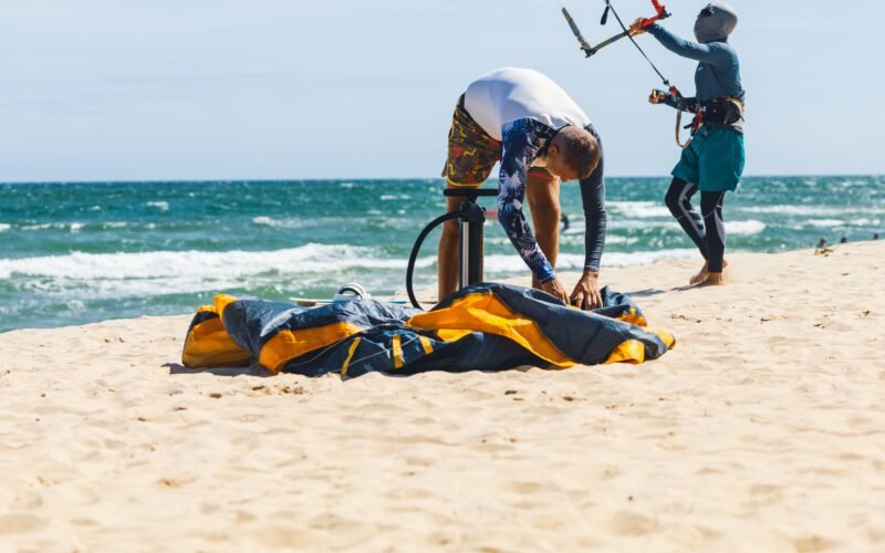 Un rider gonflant son aile de kitesurf sur la plage avant une session