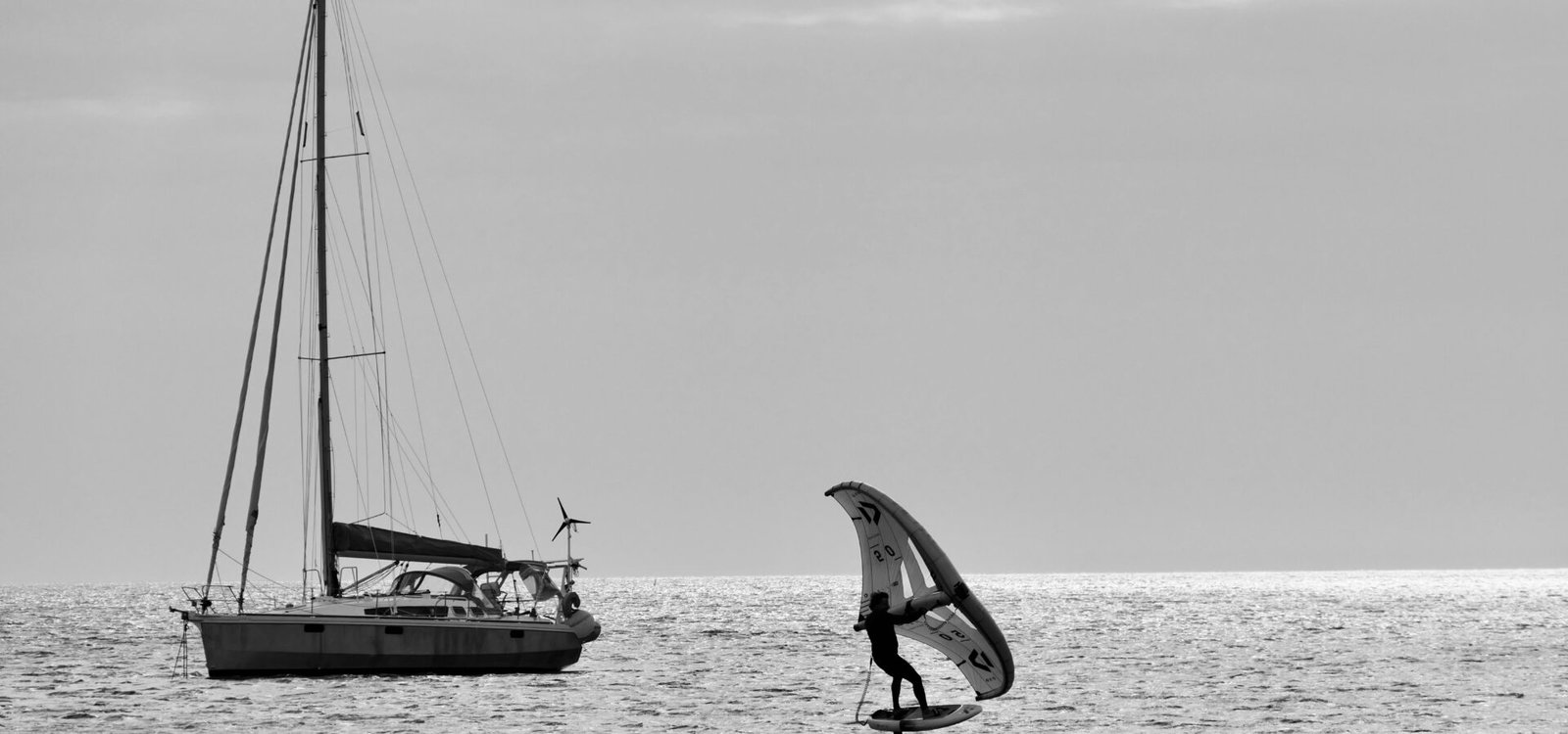 Un rider de wing foil tenant son aile gonflable au-dessus de l'eau