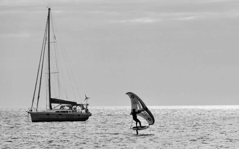 Un rider de wing foil tenant son aile gonflable au-dessus de l'eau