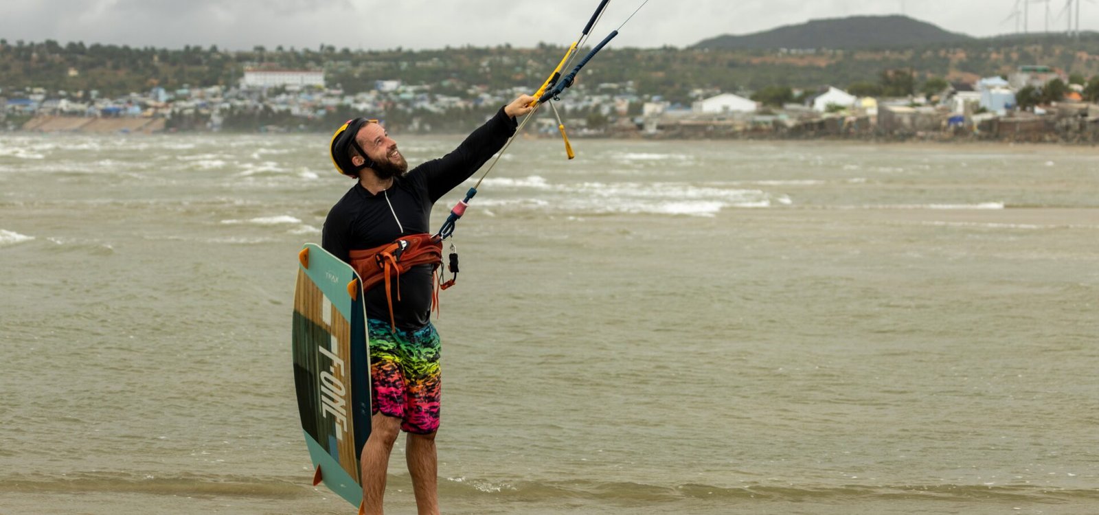 Un kitesurfeur tenant sa barre et ses lignes en position de navigation