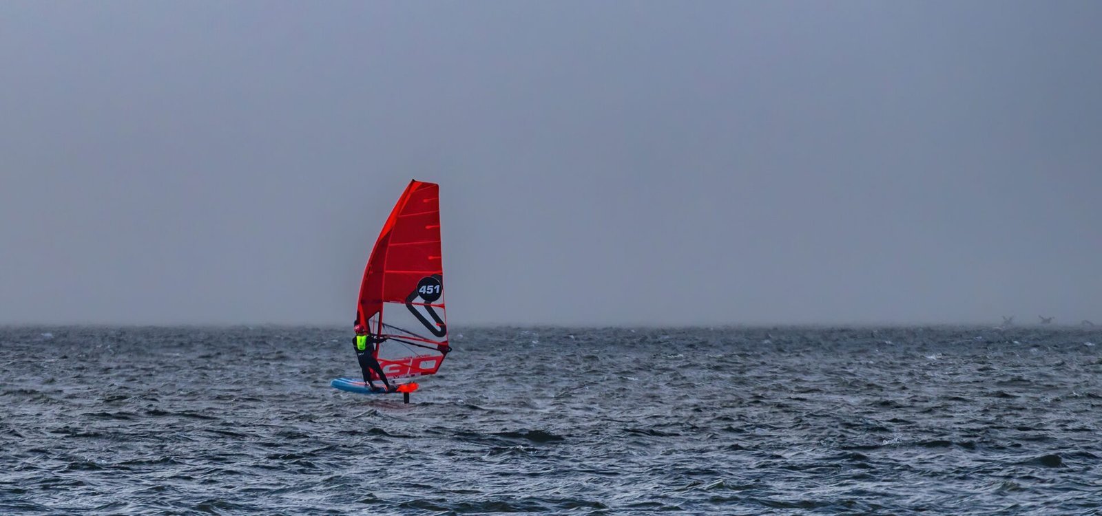 Un windsurfeur naviguant dans une eau formée près de la côte