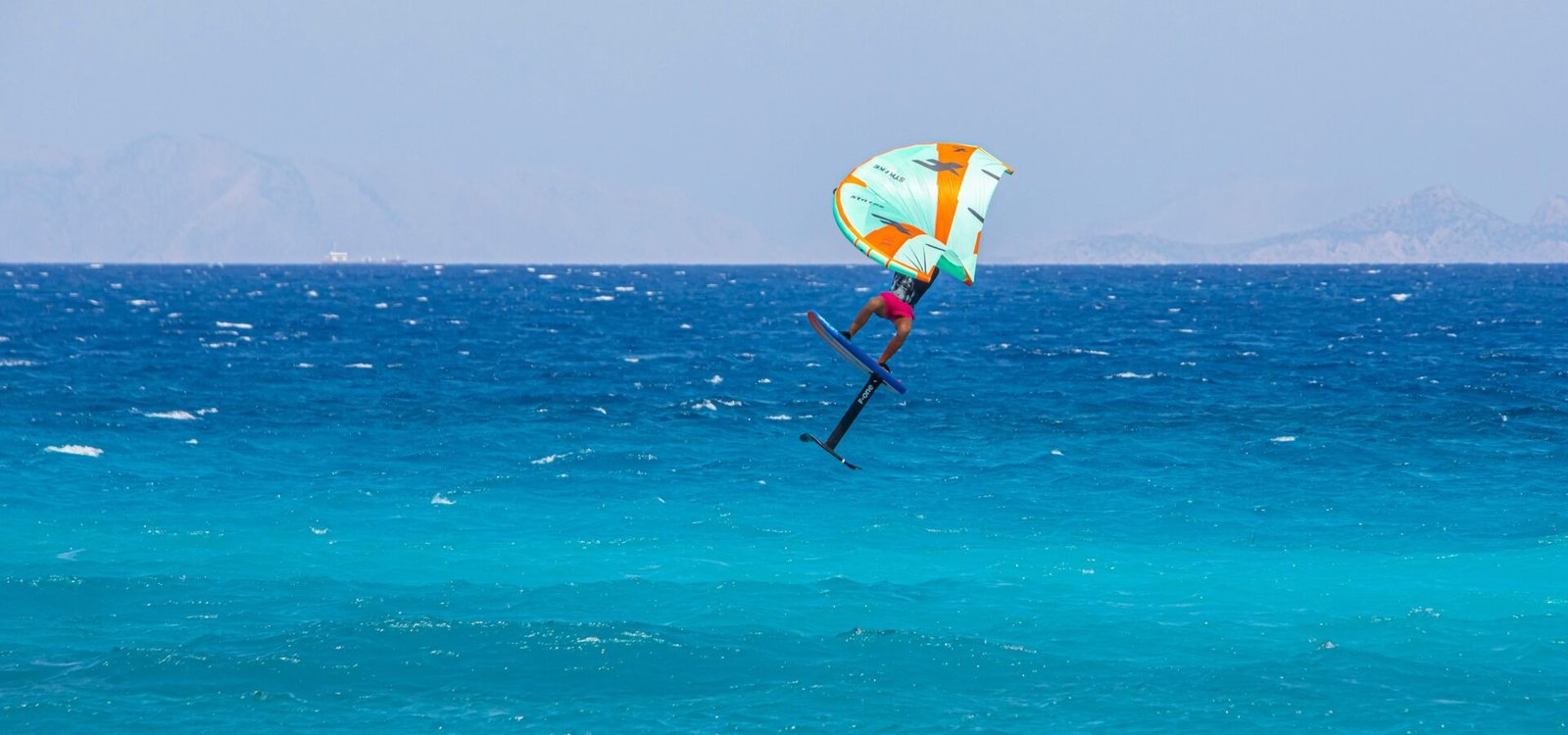 Un rider de foil en plein vol au-dessus de l'eau turquoise