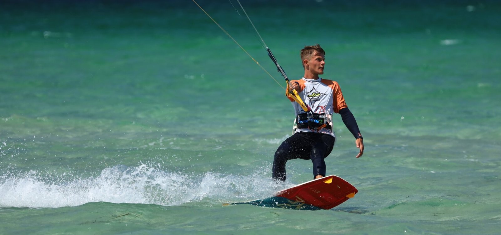 Un kitesurfeur avec son twintip sous le bras face à la mer