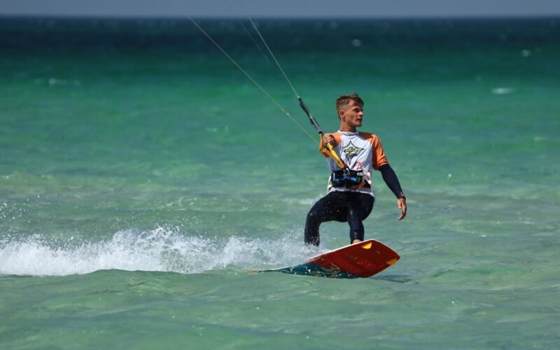 Un kitesurfeur avec son twintip sous le bras face à la mer