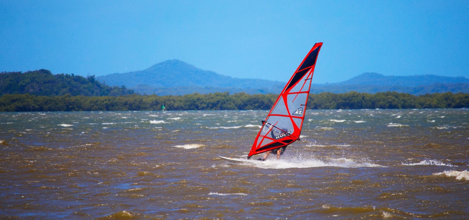 Une voile de windsurf gréée sur la plage avant une session