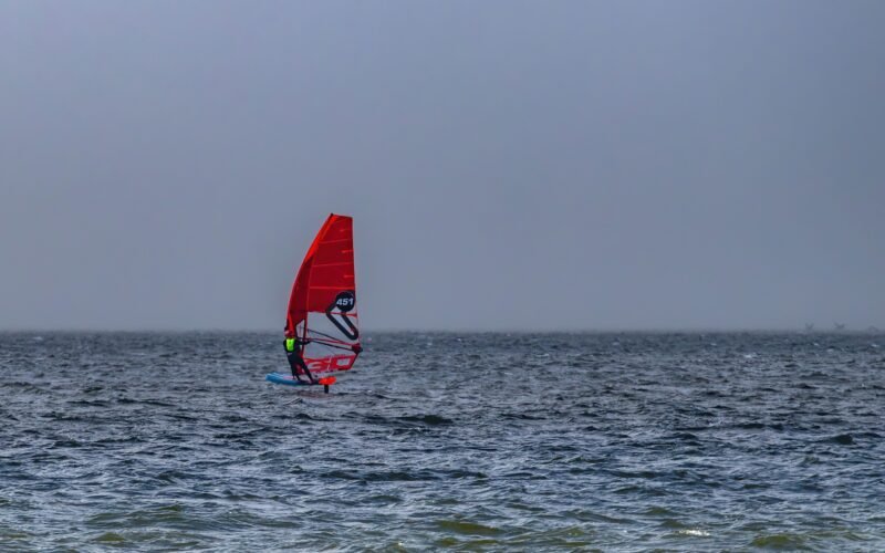 Un windsurfeur tenant le wishbone de sa voile en pleine navigation